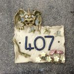 Dragon sitting on top of house number plaque